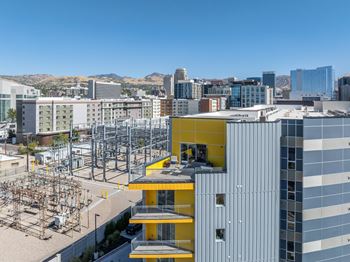 A modern building with a yellow section in the middle is in the foreground of a cityscape.